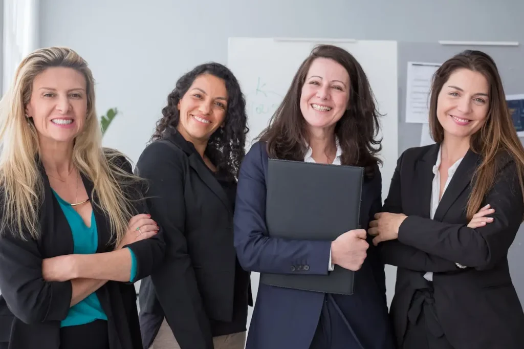 Smiling diverse group of professional women celebrating success at work through creative side hustles for women.
