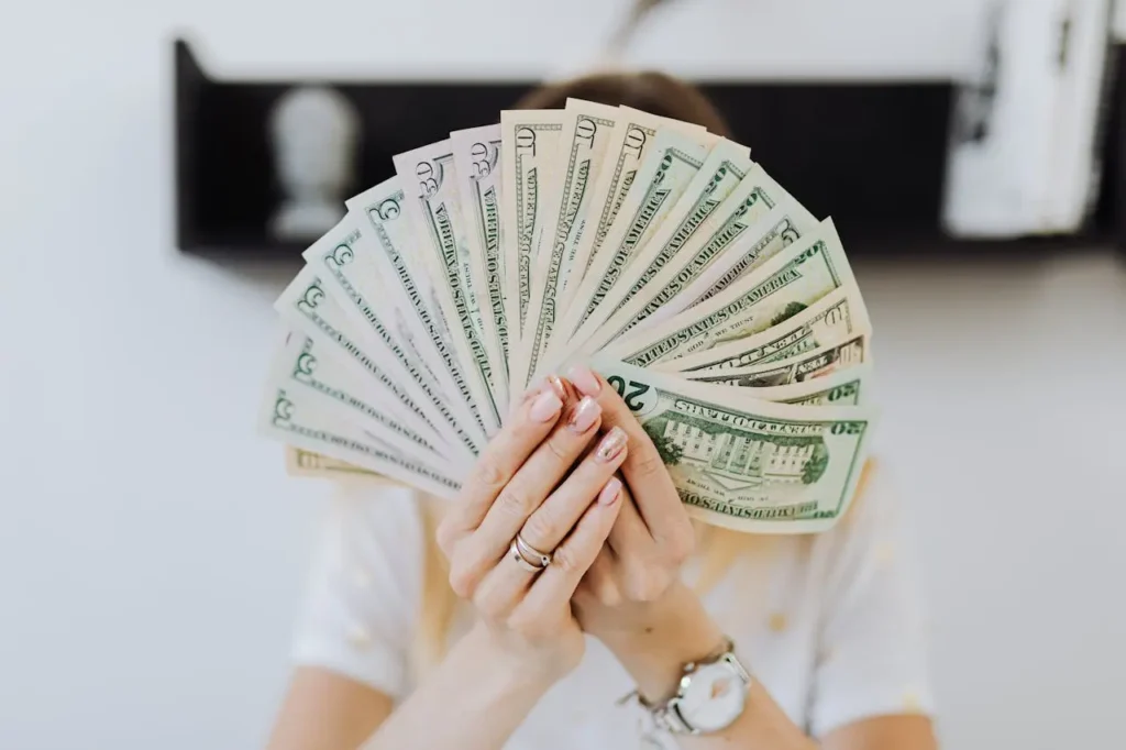 Person holding a fan of U.S. dollar bills, symbolizing extra income from the best side hustles in the USA.