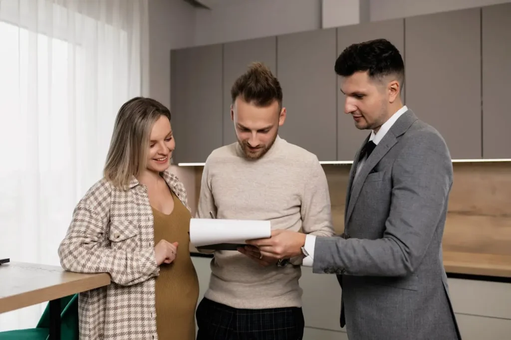 Young couple reviewing insurance documents with a financial advisor in a modern home setting, discussing the best life insurance options.