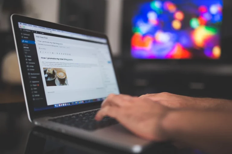 Person typing a blog post on a laptop screen using WordPress with a colorful screen in the background, representing passive income ideas through blogging.