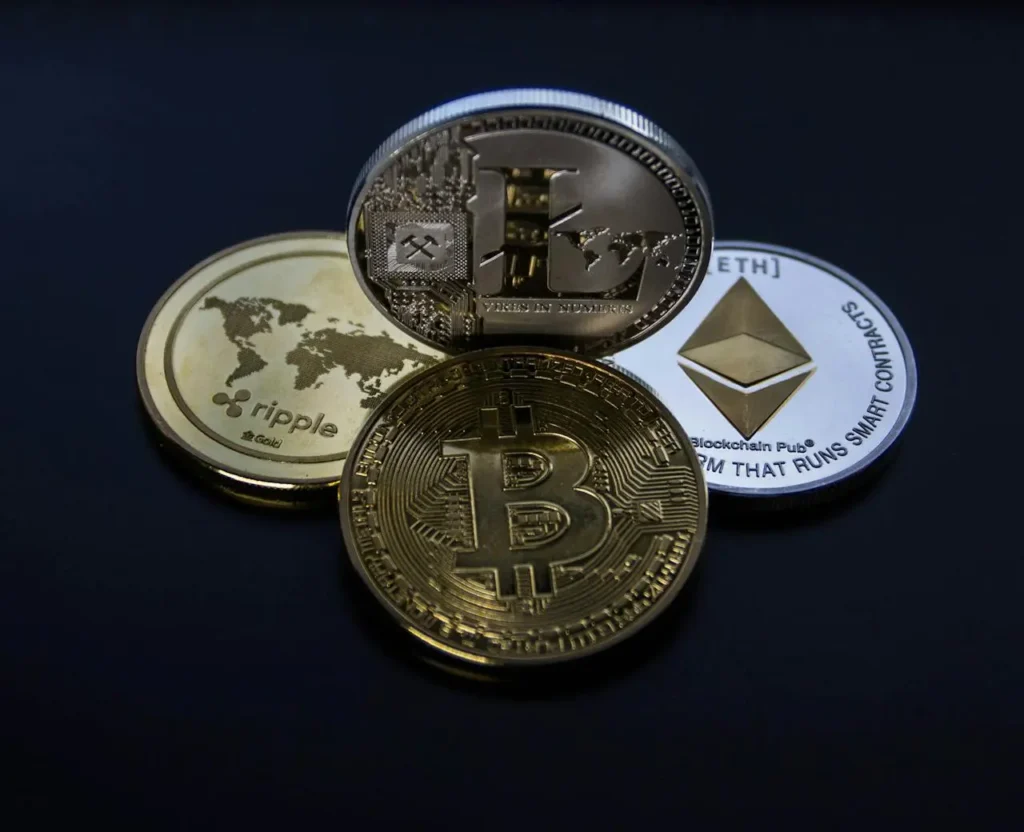 Physical coins representing popular cryptocurrencies Bitcoin, Ethereum, Litecoin, and Ripple on a dark background, symbolizing cryptocurrency investing.