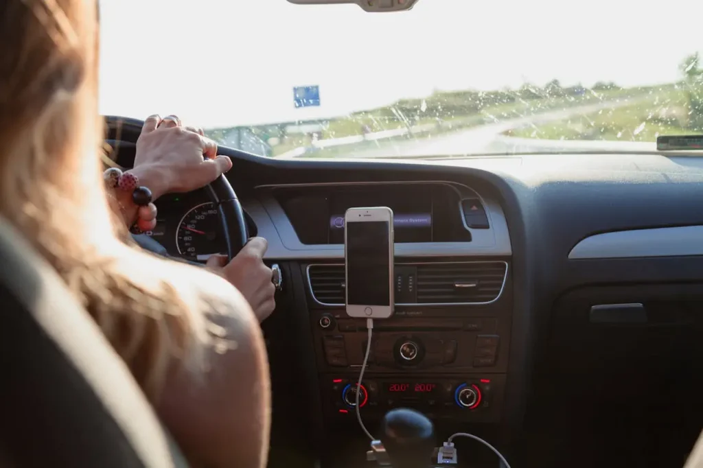 Person driving a car with a smartphone mounted on the dashboard for navigation, illustrating how to make money driving through gig economy apps.