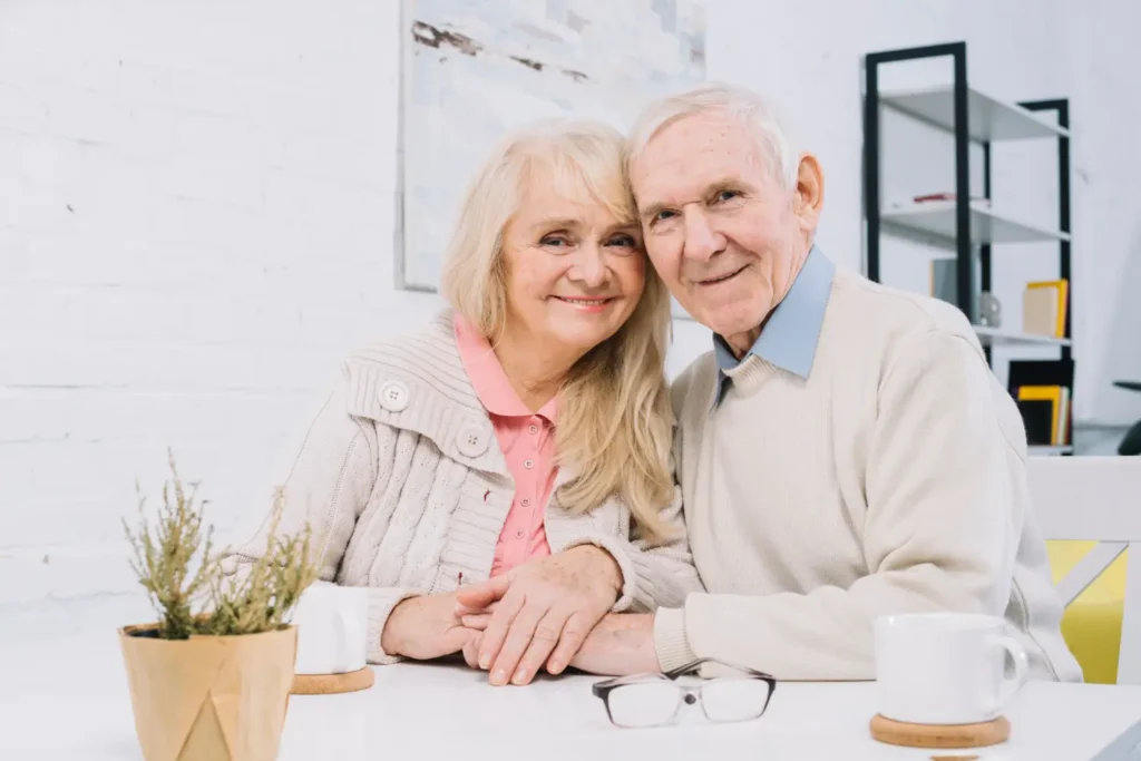 Smiling senior couple sitting together at a table, symbolizing retirement and Medicare support.