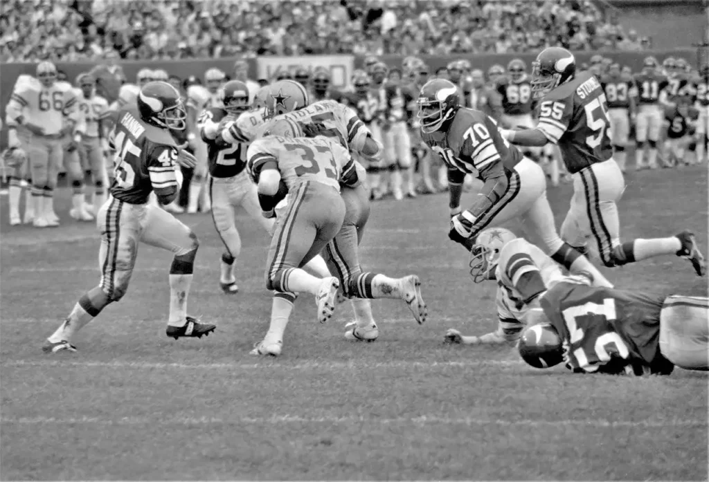 Black and white photo of a classic NFL game between the Minnesota Vikings and Dallas Cowboys, showcasing the historical legacy of a U.S. sports franchise.