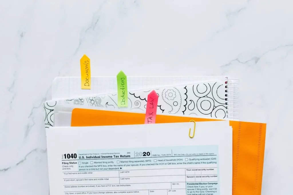Stack of tax documents with colorful tabs labeled "Documents," "Deductions," and "Tax Law" next to a U.S. 1040 form, related to personal loan interest tax-deductible rules.