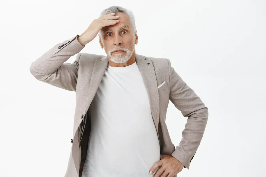 Worried senior man holding forehead, realizing critical life insurance mistakes in a financial decision.