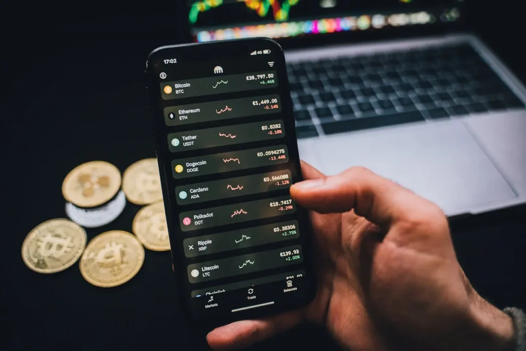 Person holding smartphone displaying live cryptocurrency prices, with Bitcoin and other crypto coins in the background—illustrating how to find new cryptocurrencies.