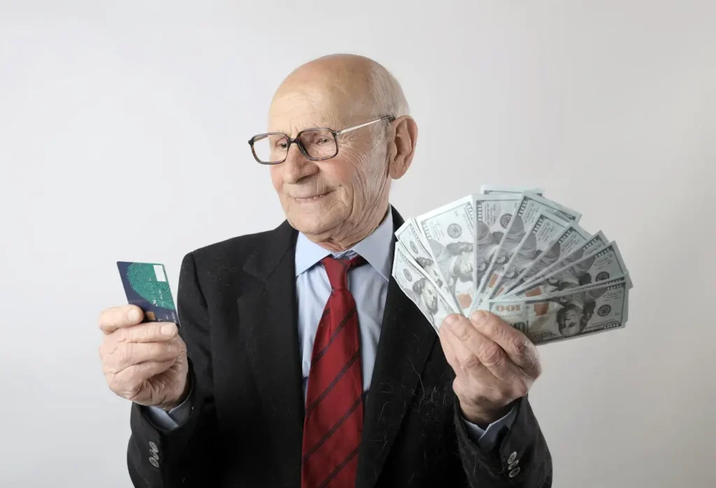 Elderly man in a suit comparing a credit card and cash to understand the advantages of credit cards over cash in modern personal finance.