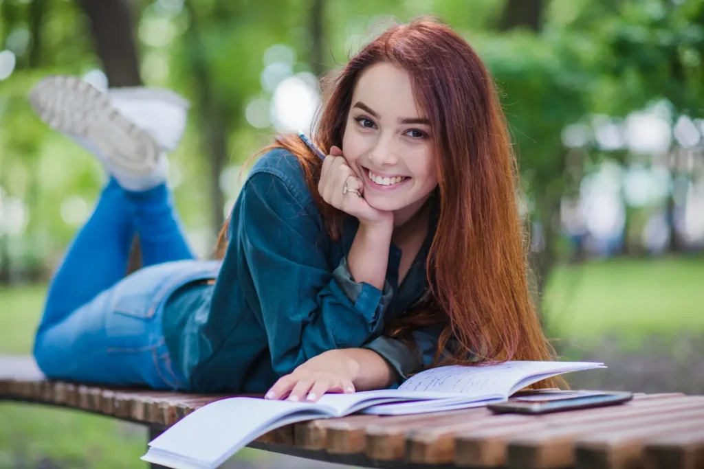 Confident college student studying outside with notebooks, representing motivation to repay student loans successfully.
