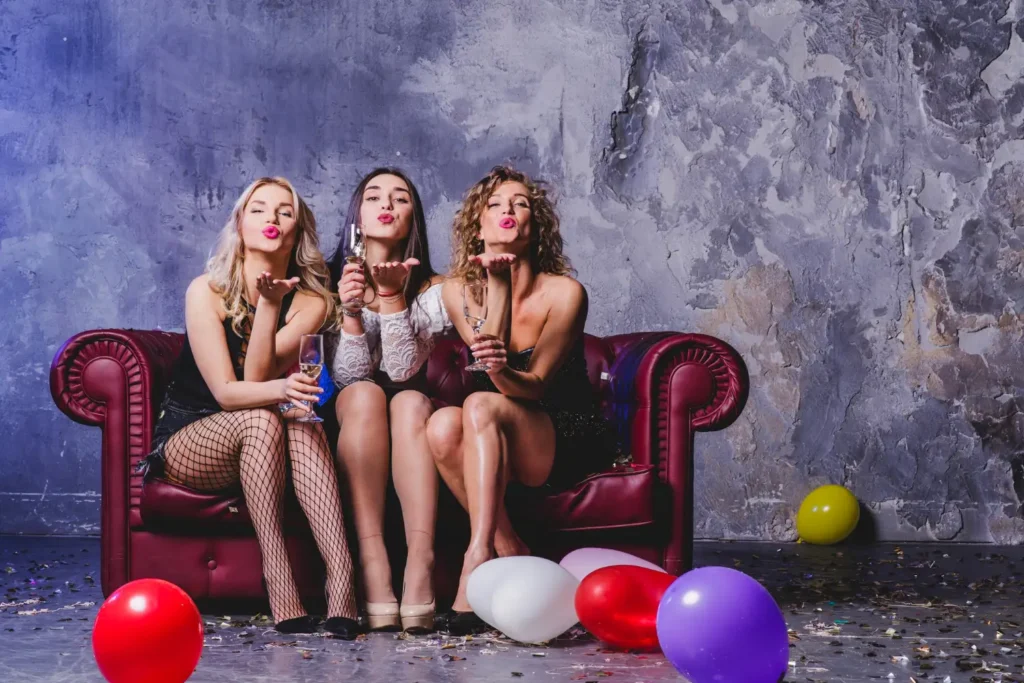 Group of friends celebrating a birthday with balloons and champagne while enjoying free birthday offers.